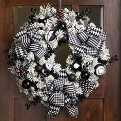 a wreath with black and white decorations hanging on a door