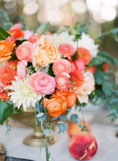 an arrangement of peaches, roses and other flowers in a vase on a table