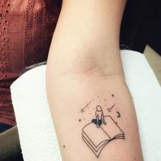 a woman's arm with a tattoo on it that has a book and stars