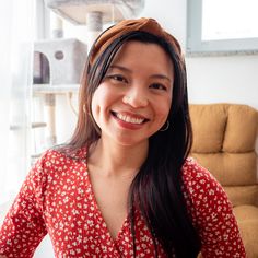 a woman sitting in front of a window smiling at the camera with her hands on her hips