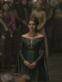 the queen in green gown standing next to other people and looking off into the distance