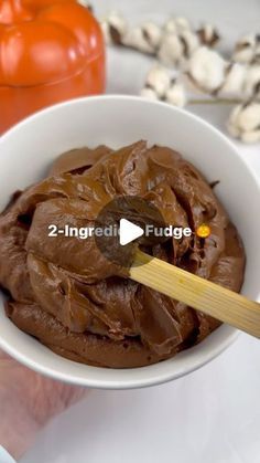 a white bowl filled with chocolate frosting next to some pumpkins and other vegetables