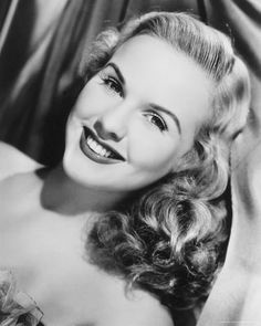 an old black and white photo of a woman smiling