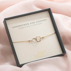 a gold bracelet in a gift box on a pink blanket with the caption godmoter and godson linked for a life - time