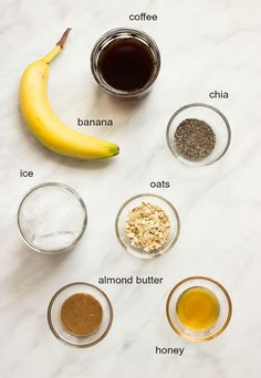 ingredients to make banana bread laid out on a white marble counter top with bananas, oats, and honey