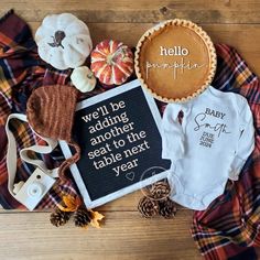 baby clothes and pumpkins are laid out on the floor next to each other, including a pie