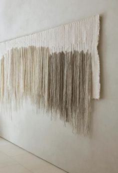 a wall hanging on the side of a white wall with fringes attached to it