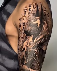 a man with a black and grey tattoo on his arm is wearing an egyptian mask