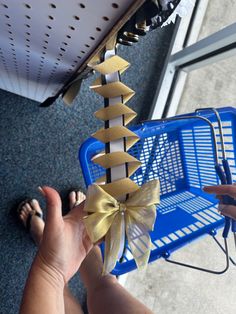 a person holding up a blue shopping cart with gold bows on it's side