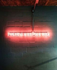 there is a neon sign that says there is a better way on the brick wall