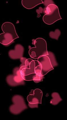 pink hearts floating in the air on a black background