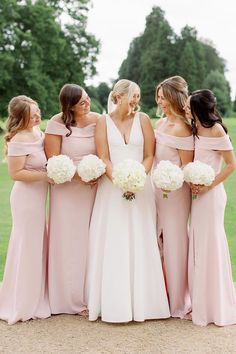 a group of women standing next to each other in front of a lush green field