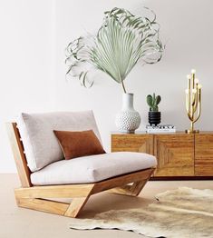 a living room with white walls and wooden furniture, including a plant in the corner