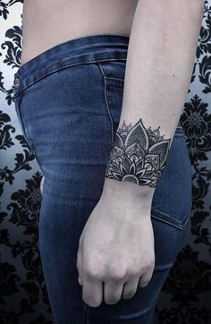 a woman's arm with a tattoo on the wrist and an intricate flower design