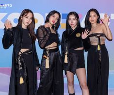 four girls in black outfits posing for the camera with their hands up and one holding her hand out