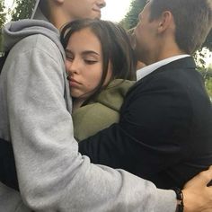 two people hugging each other in front of trees and bushes, with one person wearing a hoodie