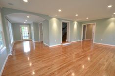 an empty living room with hard wood flooring and light blue walls in the background