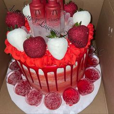 a red cake with white frosting and strawberries on top is in a box