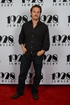 a man standing on a red carpet in front of a wall with the number twenty seventy written on it