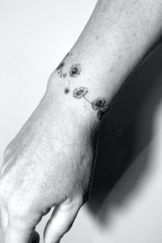 a person's hand with a flower tattoo on their left wrist and the other arm