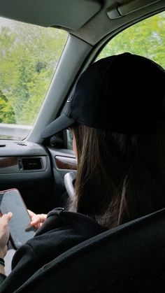 a woman sitting in the back seat of a car holding a tablet