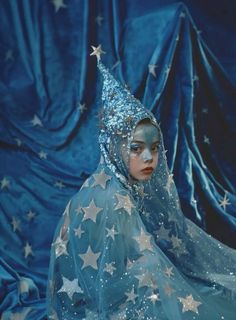 a woman wearing a blue dress with silver stars on it and a veil over her head