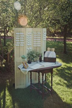 an old fashioned desk is set up in the grass with flowers and books on it