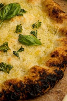 a close up of a pizza with cheese and herbs on the top, sitting on a cutting board