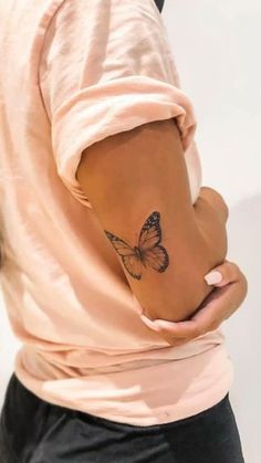 a woman with a small butterfly tattoo on her left side ribcading the back of her arm