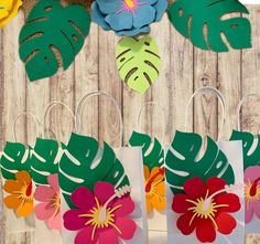 paper flowers and leaves are hanging from the side of a wooden fence with scissors on it