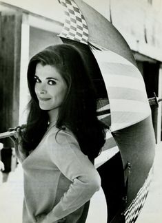 black and white photograph of a woman holding an umbrella in front of a building with checkered flag on it