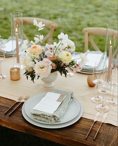 the table is set with white and pink flowers in vases, candles, napkins, and wine glasses