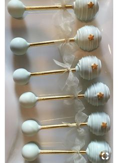 six white and gold cake pops with star decorations on them, lined up in a row