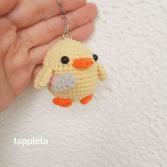 a crocheted keychain with a small yellow bird on it's face