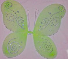 a green butterfly with white swirls on it's wings and some sparkles