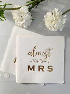 two napkins with the words almost mrs on them next to white flowers and greenery