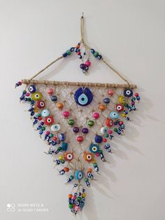 a wall hanging with beads and eyeballs on it