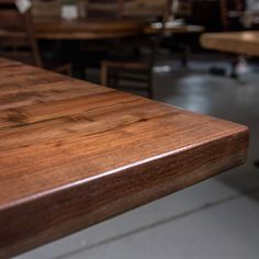 a wooden table with chairs and tables in the backgroung area behind it