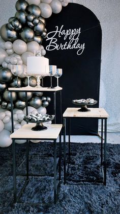 two tables with silver and white balloons in the shape of a happy birthday sign on it