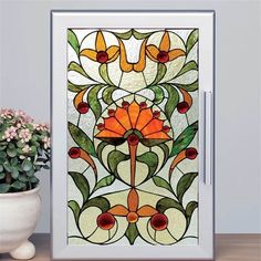 a vase with flowers sitting next to a stained glass paneled wall hanging on a wall