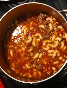 a pot filled with pasta and meat soup on top of a stove burner oven