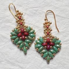 two pairs of green and red beaded earrings on top of a white cloth covered table