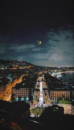 an airplane is flying over a city at night with lights on the streets and buildings