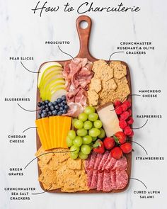 a cutting board with different types of cheeses, crackers and fruit on it