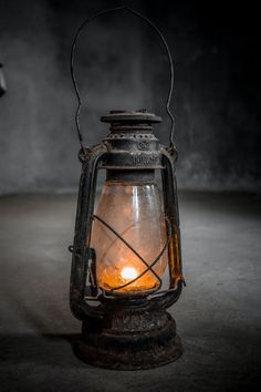 an old fashioned lantern is lit up in the dark