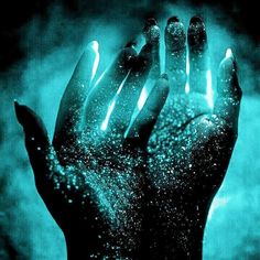 a person's hand covered in blue and black glitter with their fingers spread out