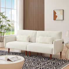 a living room with a white couch and black and white rugs on the floor