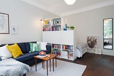 a living room filled with furniture and bookshelves next to a white rug on top of a hard wood floor