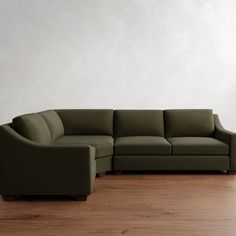 a green couch sitting on top of a hard wood floor next to a white wall