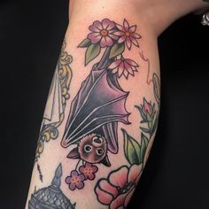 a woman with a bat tattoo on her arm holding flowers and a vase in front of her